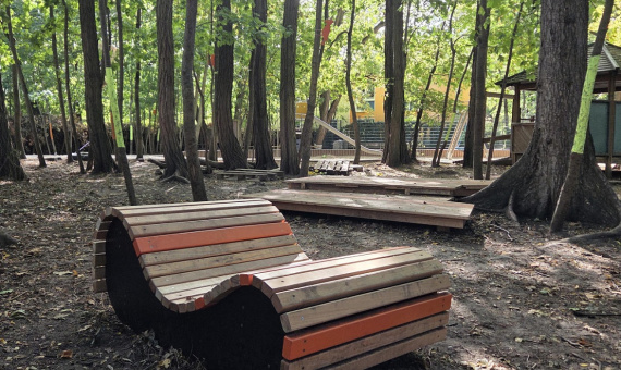 Eine Holzgartenliege steht im Wald
